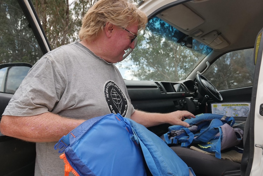 A man unpacks life jackets from his car. 