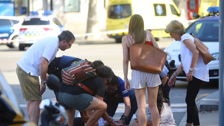 A crowd of people helps a person lying on the street.