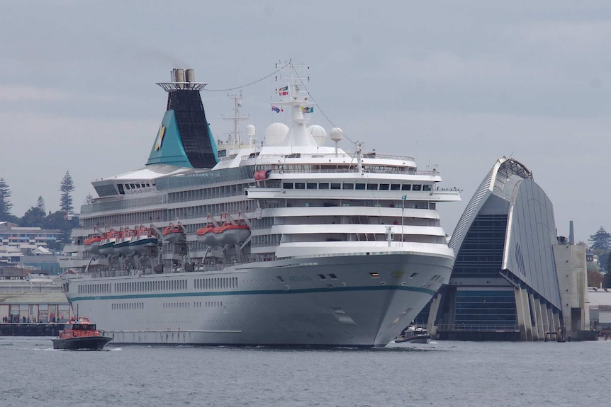 The Artania cruise ship sails away from Fremantle Port with the martime museum in the background to its left.