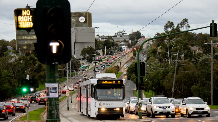 A tram travels down the centre of a highway.