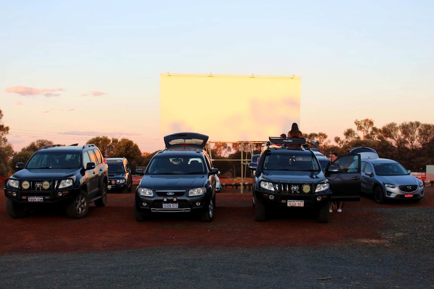 Four 4WD vehicles in a row facing a plain white projector.