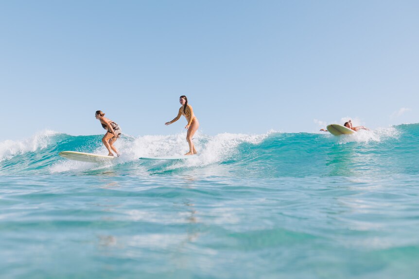 three women surfing on waves