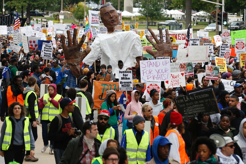 Protesters march in a rally with a paper mache representation of Michael Brown with his hands up, in St. Louis, Missouri, October 11, 2014.