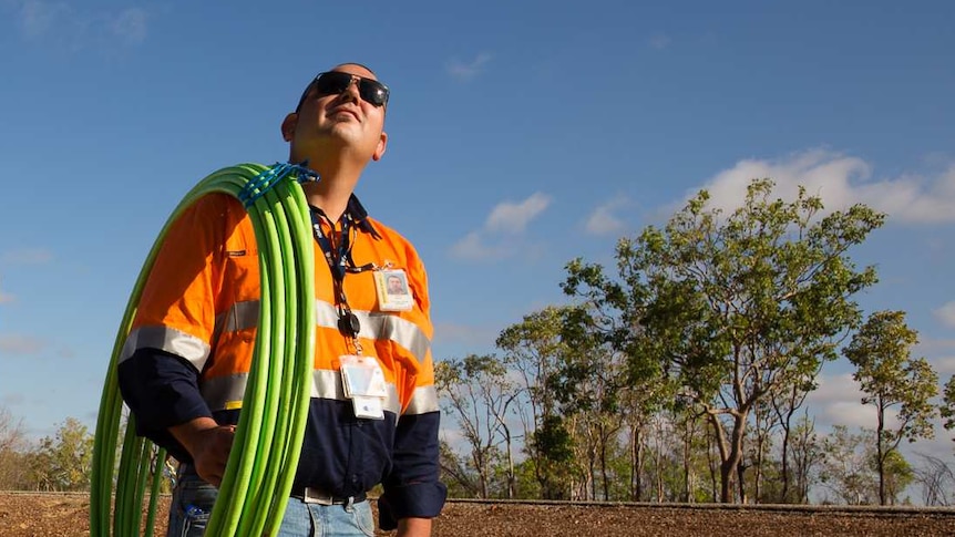 An NBN installer looks to the sky with cable over his shoulder