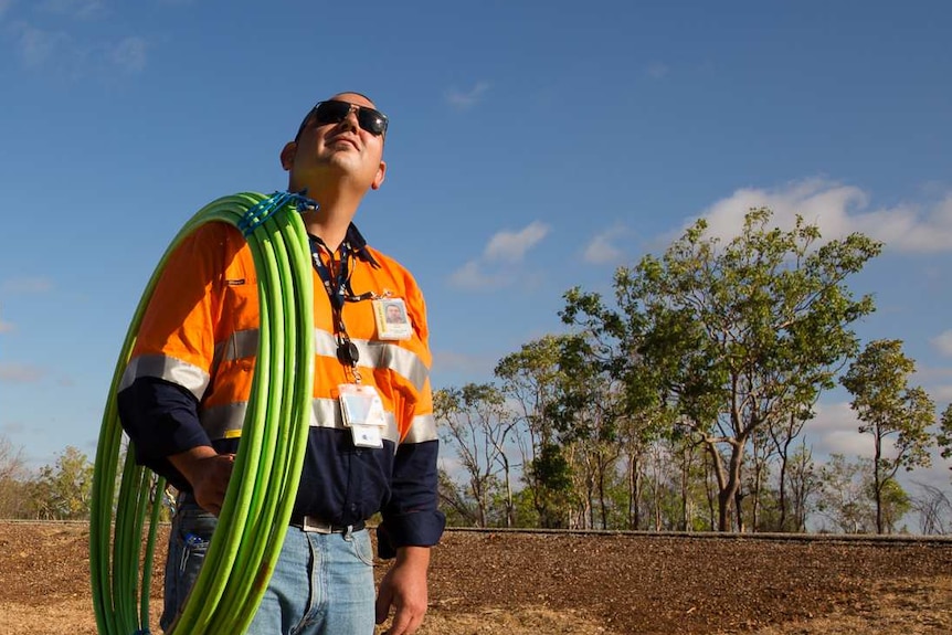 An NBN installer looks to the sky with cable over his shoulder