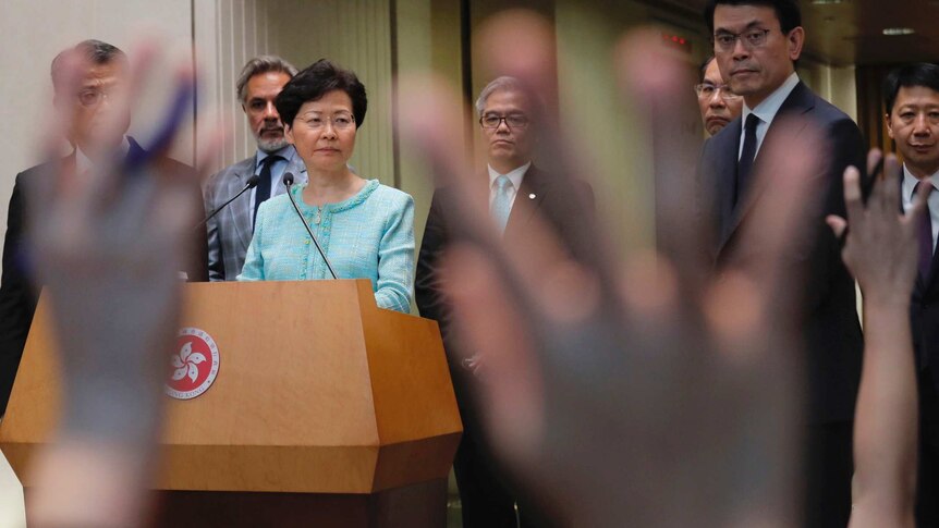 Carrie Lam wearing a blue suit answers questions at a press conference.