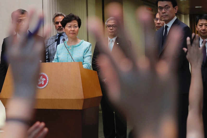 Carrie Lam wearing a blue suit answers questions at a press conference.