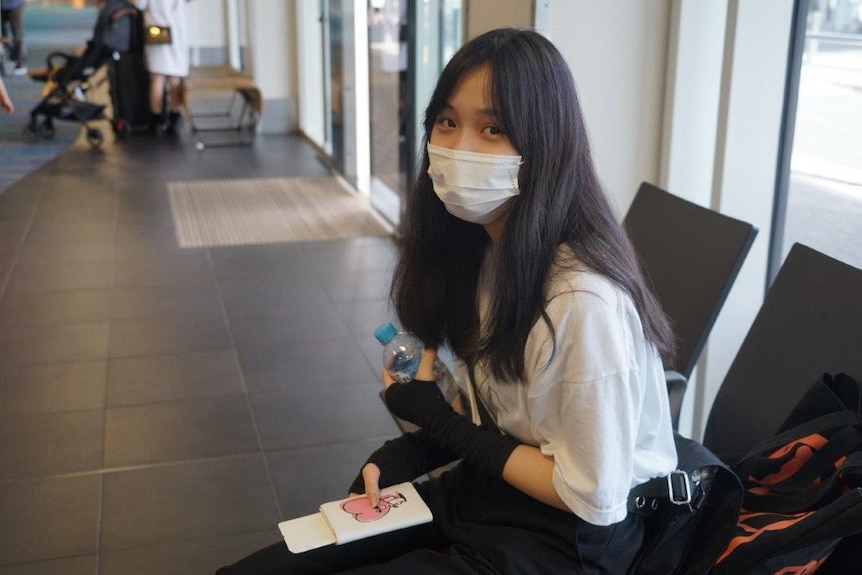 A woman waits at Darwin airport after spending 14 days in quarantine at Howard Springs.