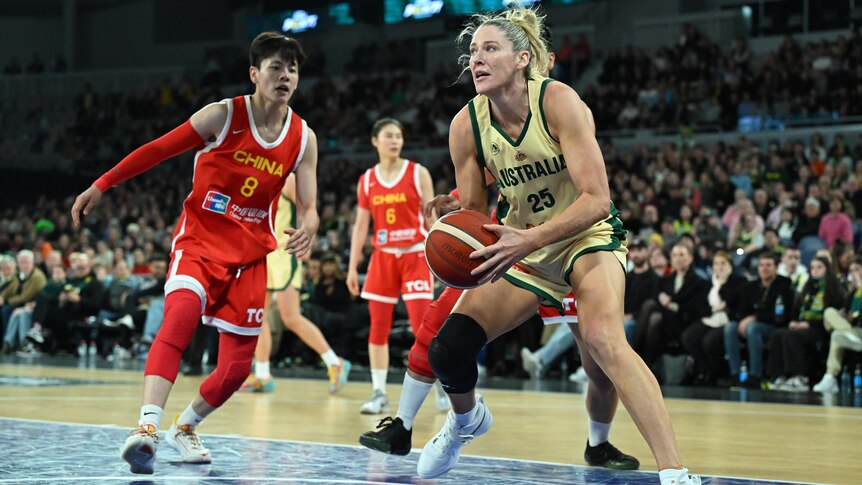 A player holding a basketball with two opponents to her side during a game