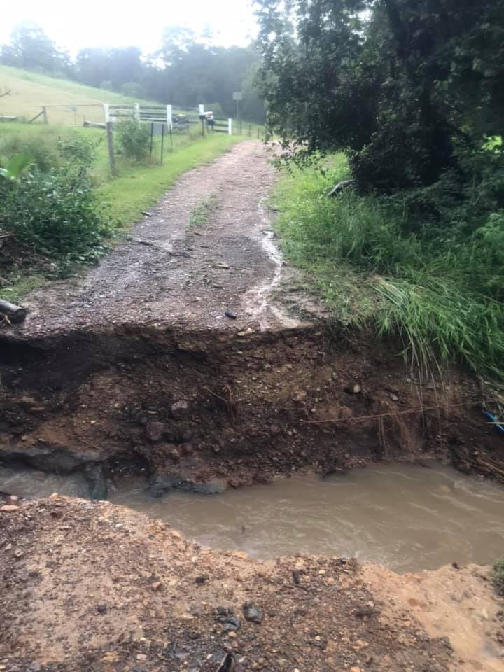A road, washed out through the middle by a swollen creek.