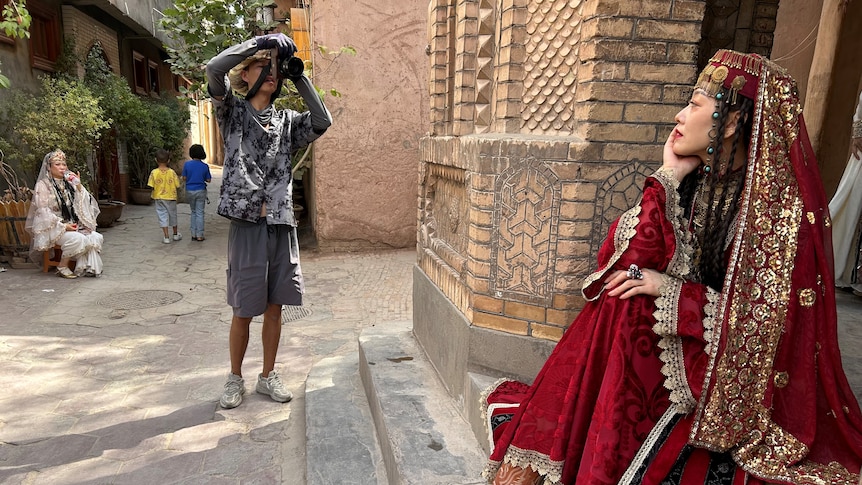 A woman in traditional Uyghur garb poses for a photo 