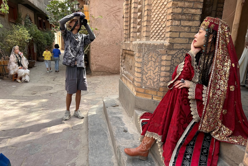 A woman in traditional Uyghur garb poses for a photo 