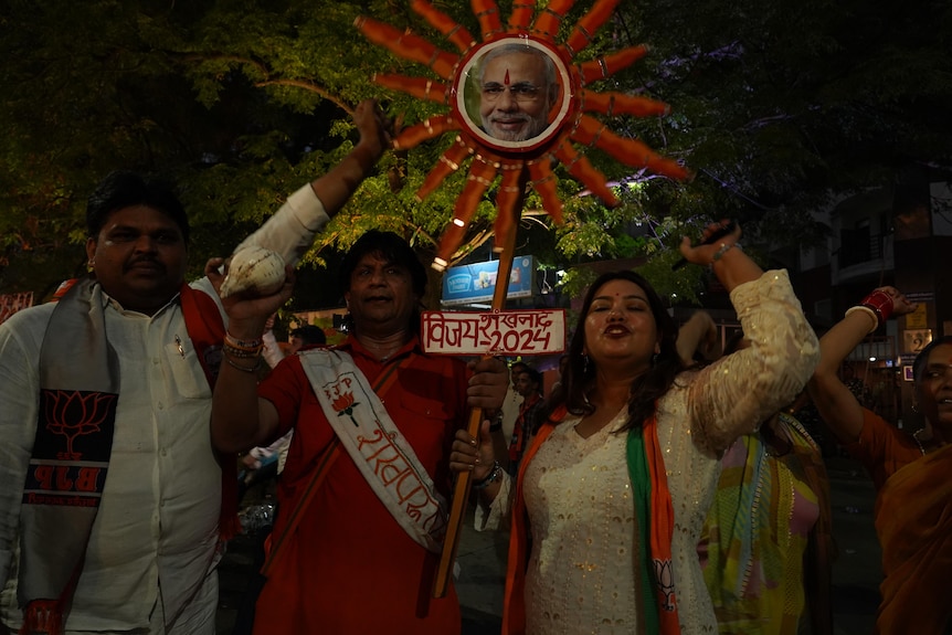 People on a street hold a picture of Narendra Modi 
