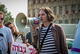 A teenager with a brown bob speaks into a megaphone 