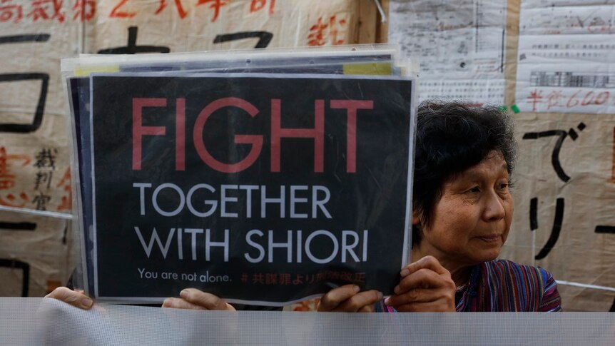 Two supporters holding up a sign saying "Fight together with Shiori"