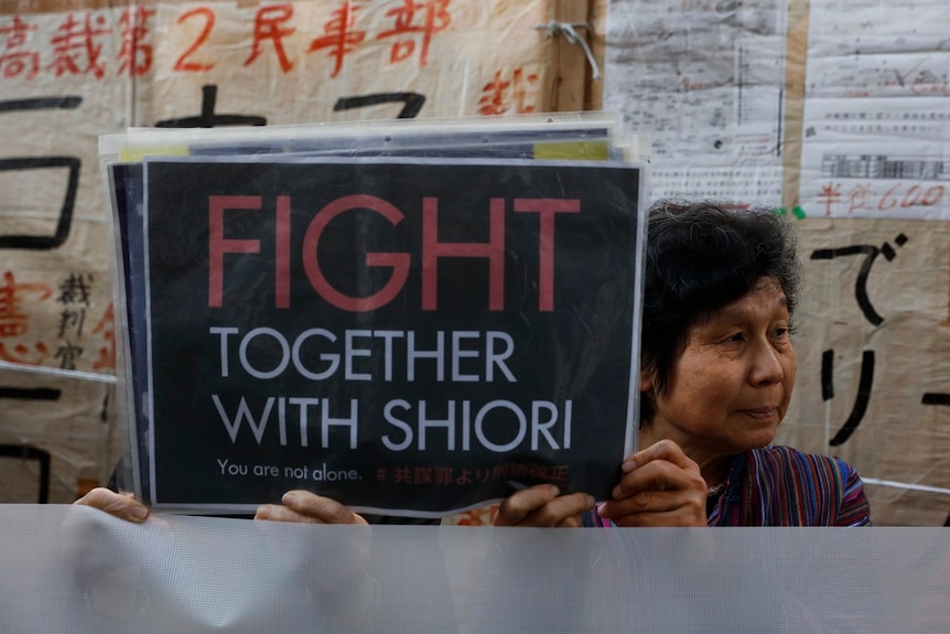 Two supporters holding up a sign saying "Fight together with Shiori"