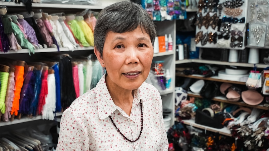 an asian woman standing in front of  materials in a shop