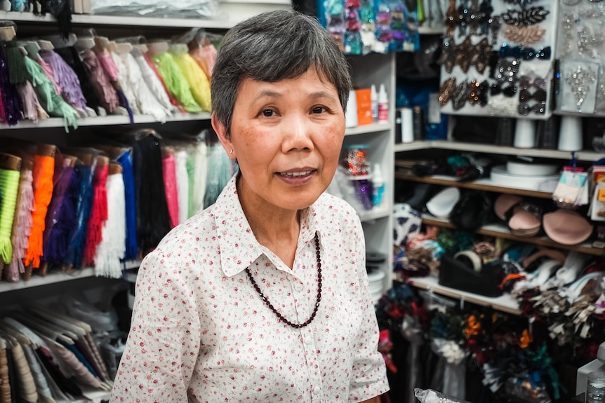 an asian woman standing in front of  materials in a shop