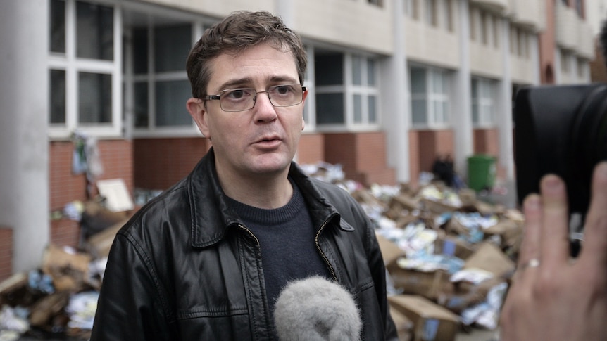 The Charlie Hebdo's publisher answers to journalists in front of the damaged offices of the French satirical magazine