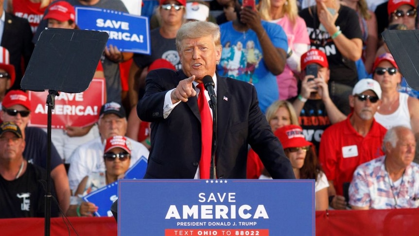 Former President Donald Trump addresses a rally, pointing at the gathered press and describing them as "Fake News"
