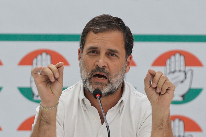 Indian opposition MP Rahul Gandhi wears a white polo top and gestures as he addresses the media.