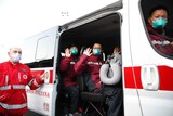 Medics and paramedics from China salute as the board a Red Cross vehicle upon arrival at an airport in Milan.