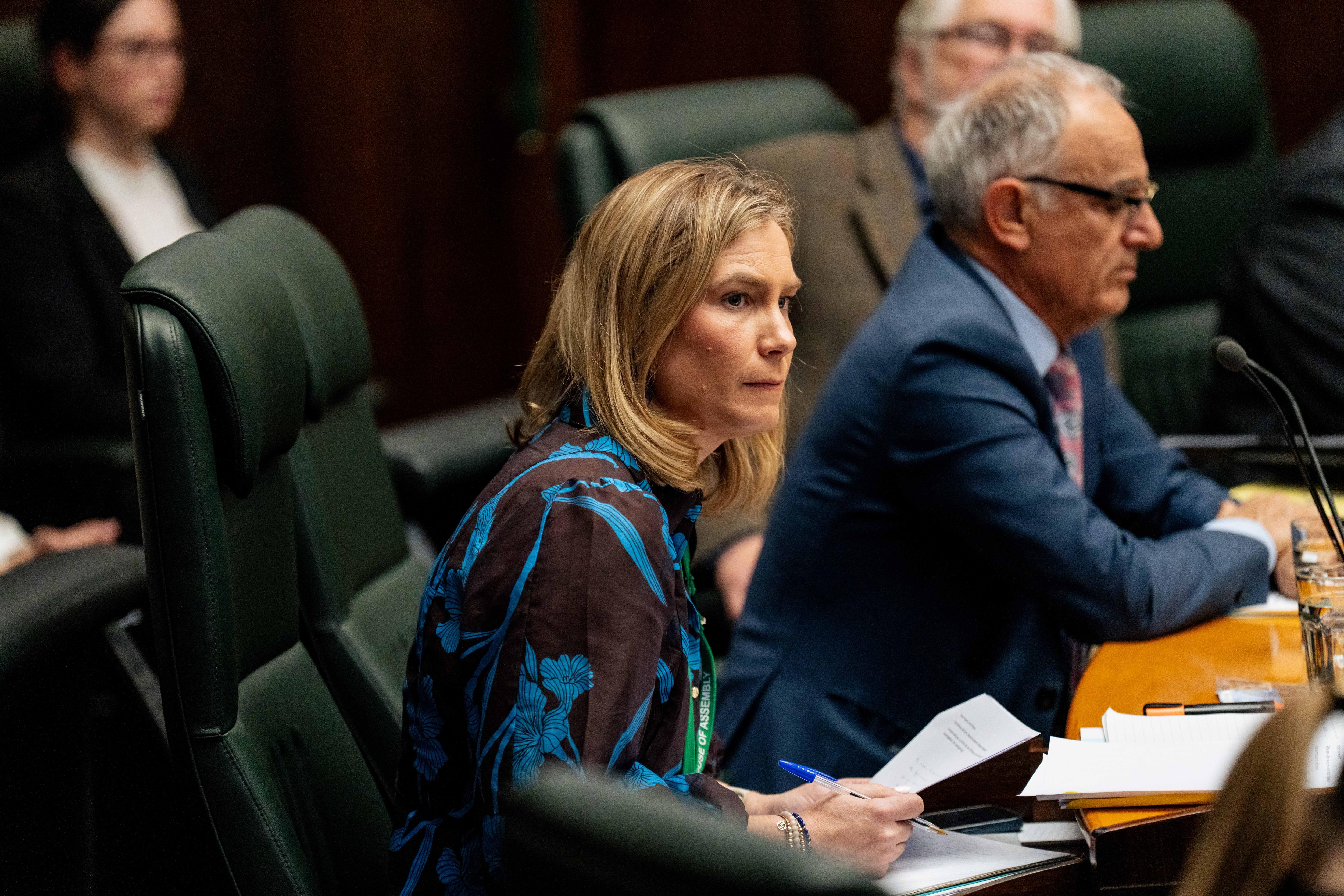 Kristie Johnston sits in parliament holding a paper in her hand.