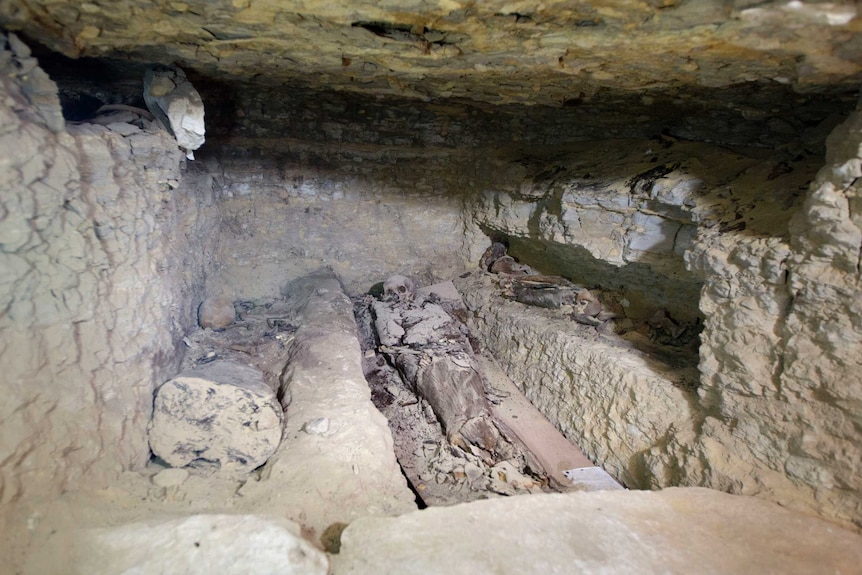 The remains of a skeleton are seen in an underground chamber.