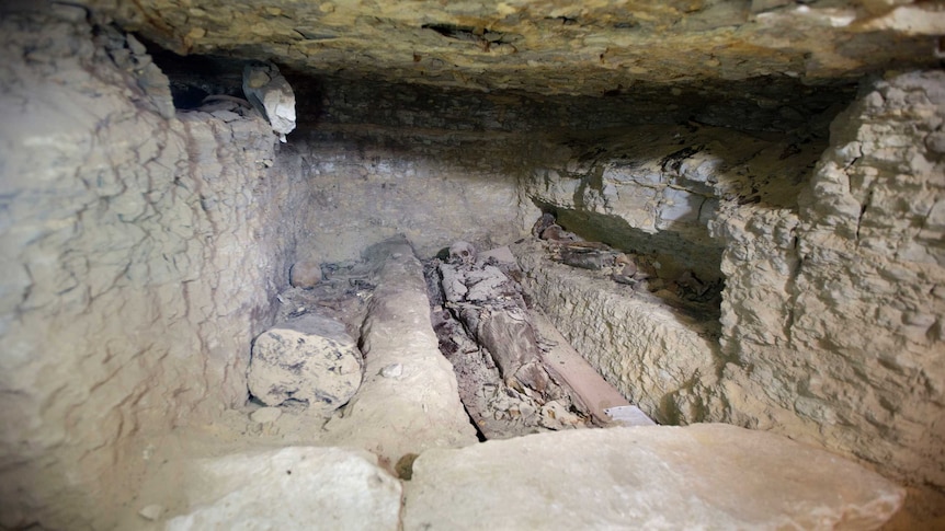 The remains of a skeleton are seen in an underground chamber.