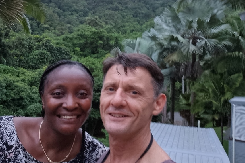 A selfie of two people with rainforest in background