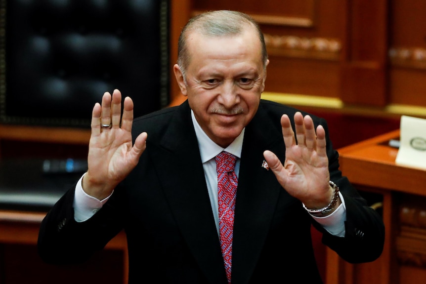 Recep Tayyip Erdogan holds two hands in the air. 