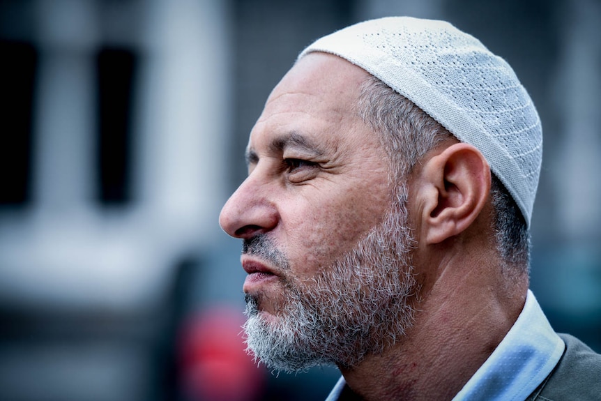 A man wearing a small religious head cap stares into the distance.