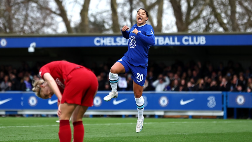 Sam Kerr jumps and punches the air after a goal against Liverpool. A red-clad player slumps in front of her.