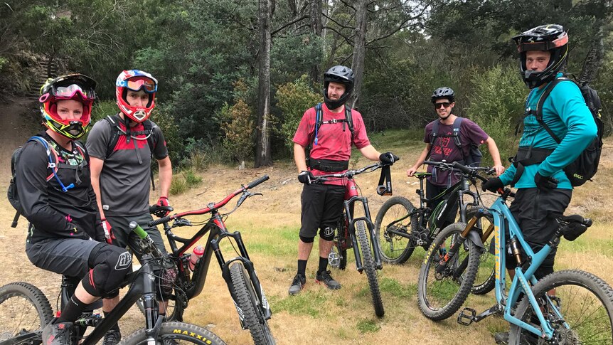 A group of five mountain bikers wearing helmets and protective clothing at the Blue Derby Mountain bike trails in Tasmania.
