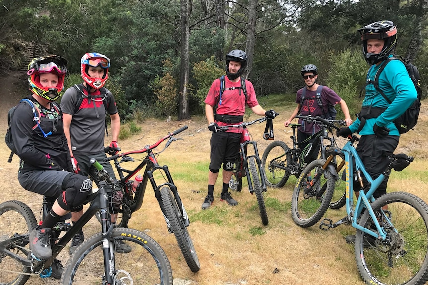 A group of five mountain bikers wearing helmets and protective clothing at the Blue Derby Mountain bike trails in Tasmania.