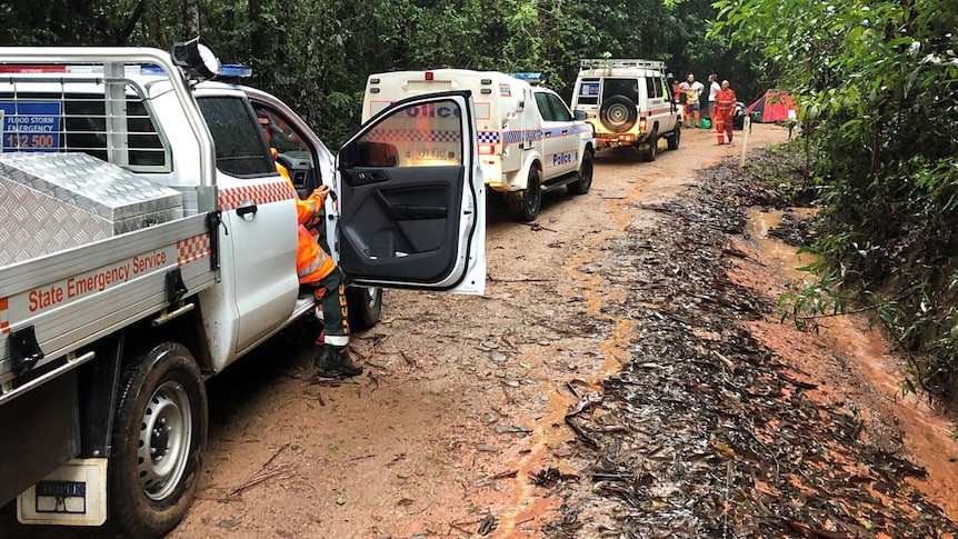 A line of emergency services vehicles on a muddy and wet dirt road in far north Queensland.