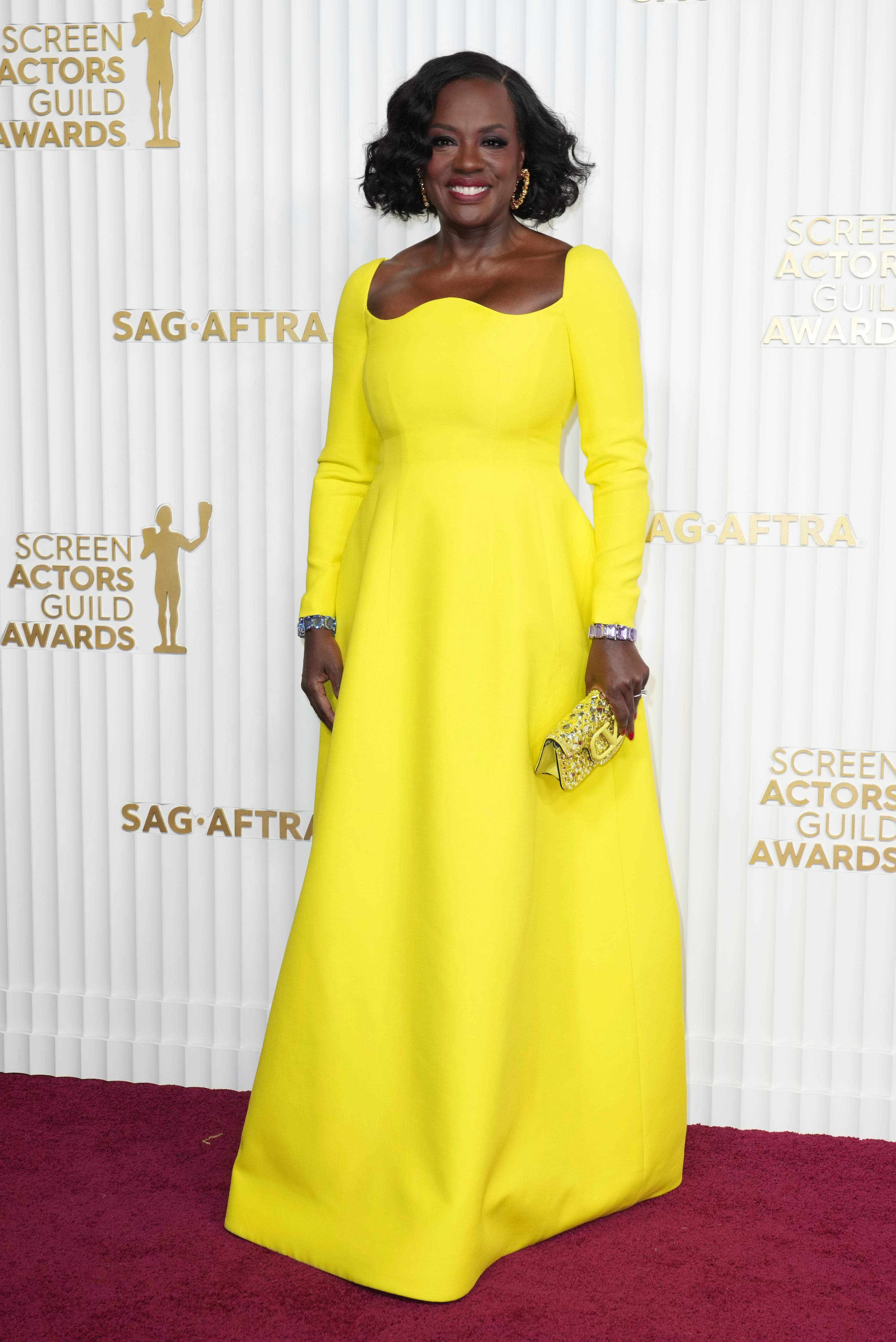 Viola Davis wearing a bright yellow floor-length gown with off-the-shoulder long sleeves with a curved boat neckline