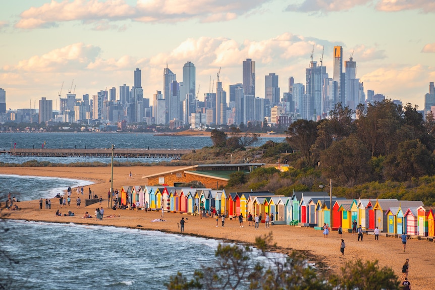 Brightly coloured beach bathing boxes with the Melbourne skyline in the background