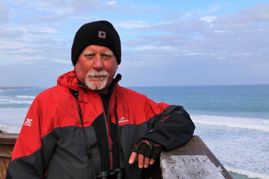 A man standing with the ocean in the background.