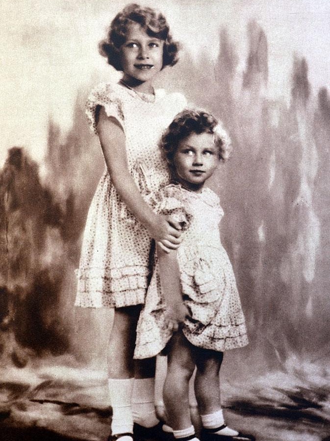 A black and white photo of little Queen Elizabeth with her arms around her sister Princess Margaret
