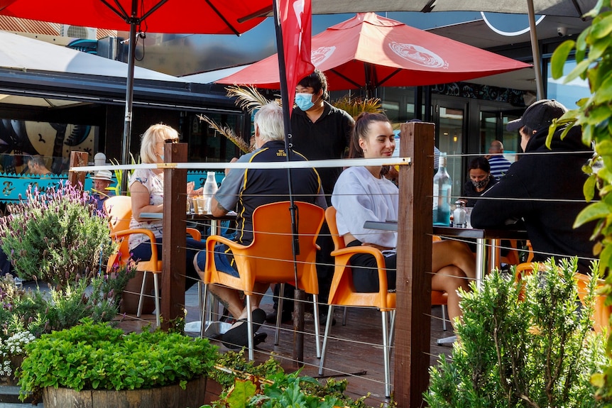 Patrons sit at a cafe in Melbourne as a waiter brings water to a table