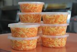 Tubs of cheese slaw stand stacked on a counter.