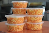 Tubs of cheese slaw stand stacked on a counter.