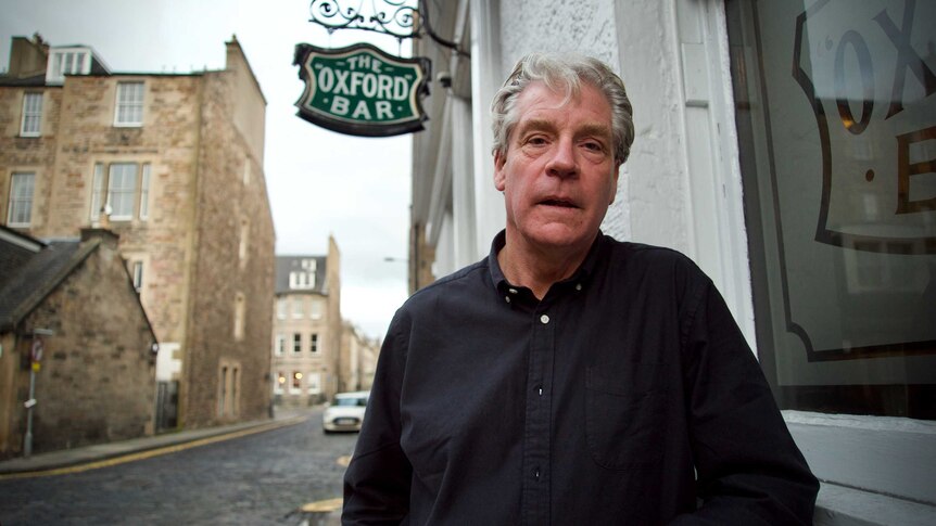 A man stands alongside The Oxford Bar pub in Edinburgh.