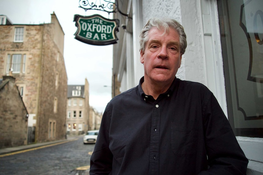 A man stands alongside The Oxford Bar pub in Edinburgh.