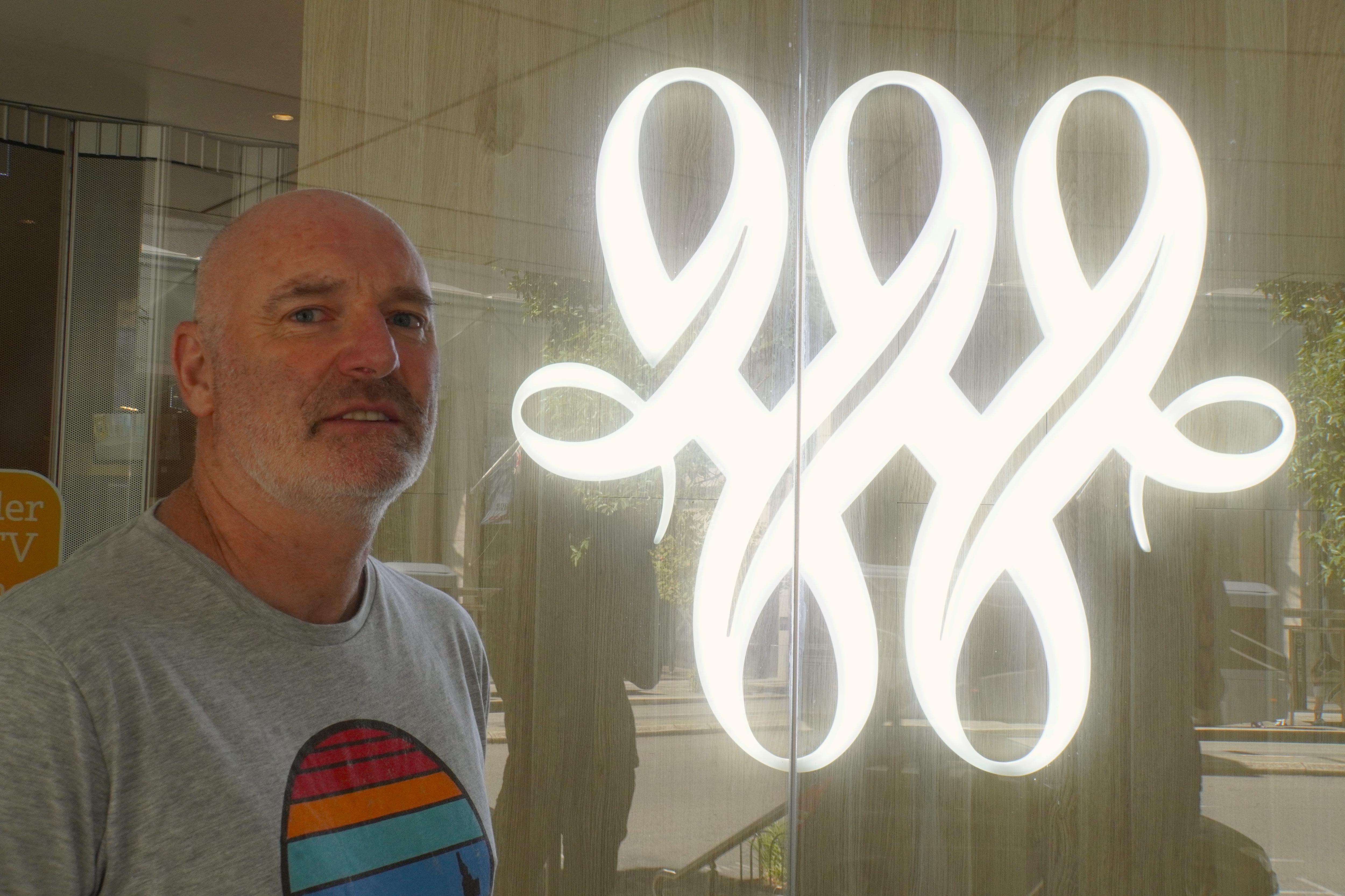 Un hombre llamado David Young parado junto al logotipo de Bankwest. 