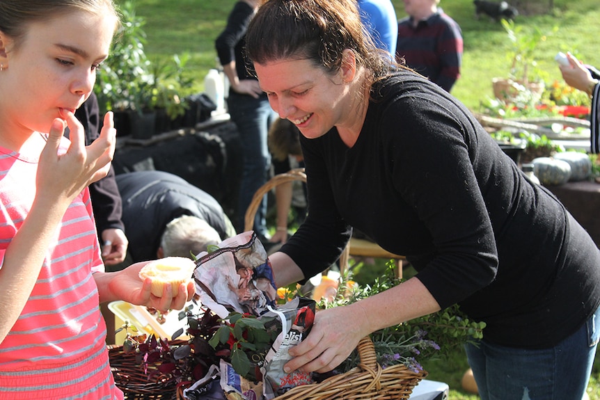 A woman bending over to smell a basket full of lavender.