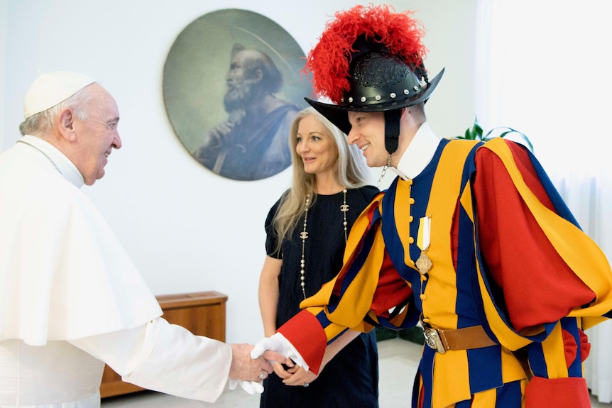 Swiss guard Dominic Bergamin in full uniform shaking hands with Pope Francis as wife Joanne looks on