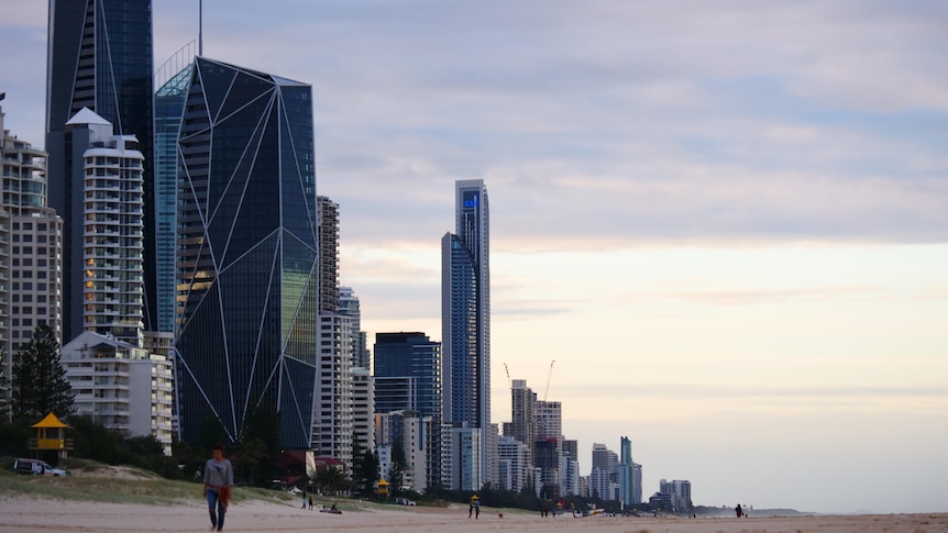 Apartment blocks tower over a beach as a sun sets on the Gold Coast. 