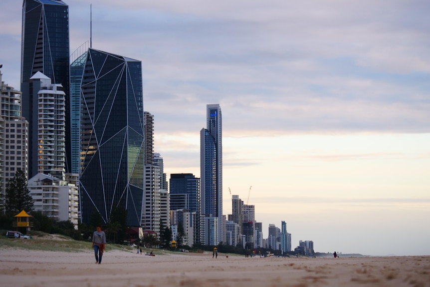 Des immeubles d'appartements dominent une plage alors qu'un soleil se couche sur la Gold Coast. 